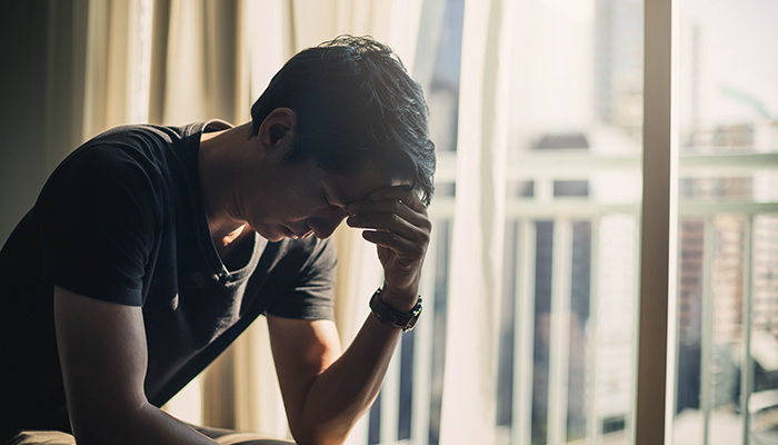 Concerned man holding head indoors