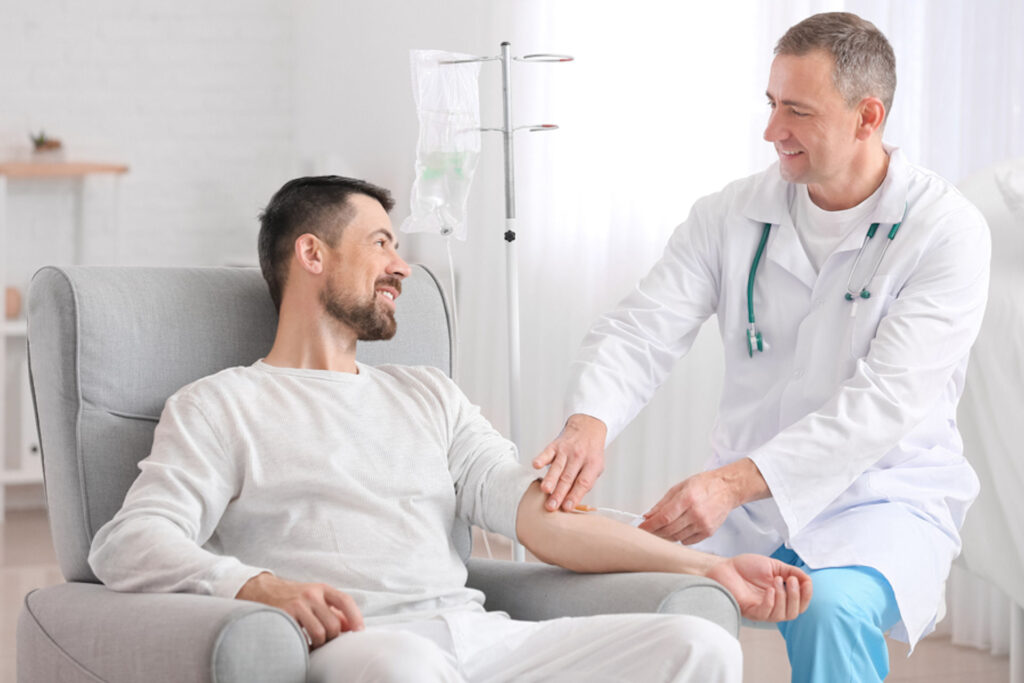 Man sitting and receiving IV therapy from doctor