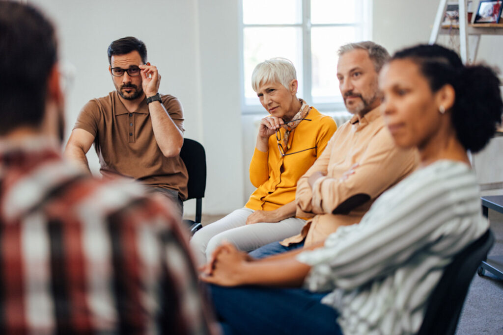 Group of people of different genders, ages, and ethnicities participating in addiction treatment group